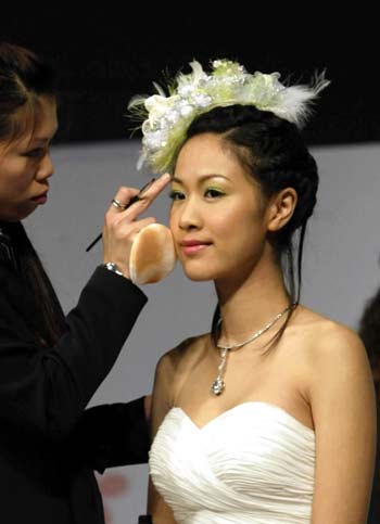 A dresser makes up for a model during a wedding dress show in Hong Kong, south China, June 3, 2006. [Xinhua]