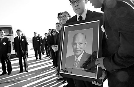 Holding a picture of his grandfather, Kenneth Fok stands among other relatives seeing off Henry Fok's coffin yesterday morning at Beijing Capital International Airport. 