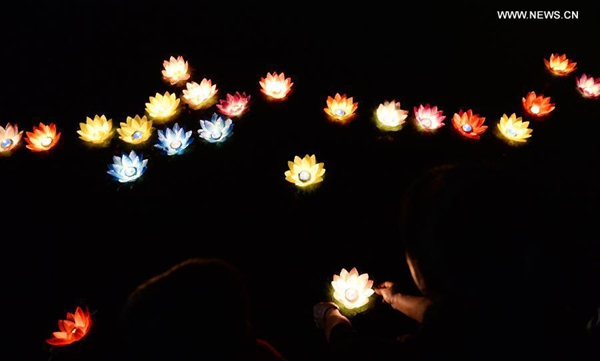 Mourners float river lanterns for the deceased