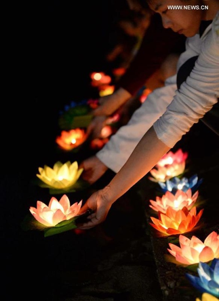 Mourners float river lanterns for the deceased