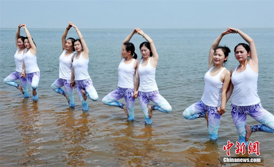 Yoga lovers stretch next to Poyang Lake