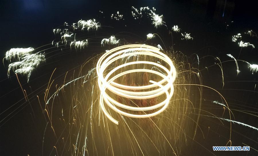 Performers spray burning iron chips to shower sparks-like fireworks