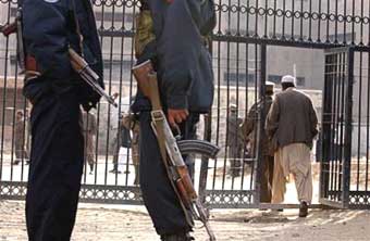 Afghan security police officers stand guard in front of the Pul-e Charkhi prison's gate in Kabul, Afghanistan Dec. 17, 2004. Two Pakistani prisoners were holed up in Kabul's main prison Friday after a bloody breakout attempt that left at least six dead and eight wounded, and sent hundreds of Afghan and international security forces racing to the scene, prison and security officials said. [AP]