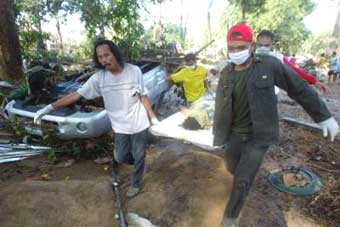 Thai rescue workers carry the dead body of a tourist in Phang Nga province, about 788 km (489 miles) south of Bangkok December 27, 2004. Soldiers searched for bodies in treetops, families wept over the dead laid on beaches and rescuers scoured coral isles for missing tourists as Asia counted the cost on Monday of a tidal wave triggered by an earthquake that killed tens of thousands. REUTERS/Chaiwat Subprasom 