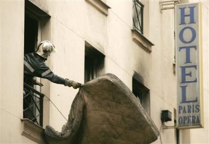 A firefighter throws a mattress from the hotel in which 21 people died, Saturday April 16, 2005 in Paris. Rescue workers sifting through the debris from Friday's fire at the Paris Opera hotel found the body of the 21st victim Friday night. Among the victims are 10 children.(AP Photo/Michel Spingler) 