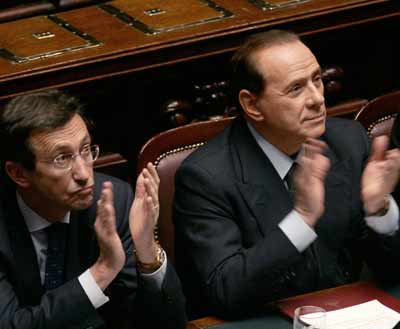 Italian Prime Minister Silvio Berlusconi (R) and Foreign Minister Gianfranco Fini applaud during a parliamentary session in Rome April 26, 2005. An angry opposition branded a report that clears U.S. soldiers of blame for killing an Italian agent in Iraq an insult to Italy on Tuesday, but Berlusconi rejected a call to discuss it in parliament. [Reuters]