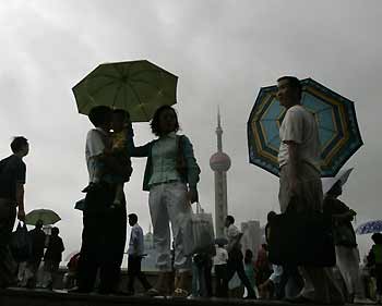 Chinese tourists walk along the Bund near the Huangpu River as dark clouds hover in Shanghai September 11, 2005. [Reuters]