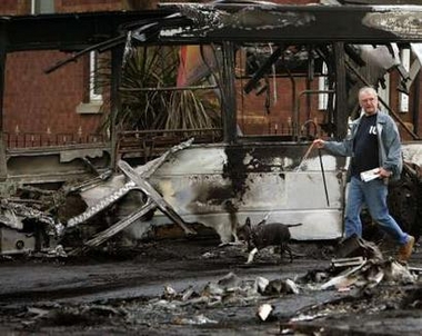 A man walks past a burnt out bus in a Loyalist area of North Belfast, northern Ireland, September 13, 2005. 