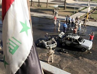 An Iraqi flag flies over the scene of a bomb attack, after a suicide car bomber rammed into an American military convoy in Baghdad's commercial and residential district of Karada, Iraq, Thursday, Oct. 27, 2005, killing one passer-by, injuring four others, Iraqi police said.(AP