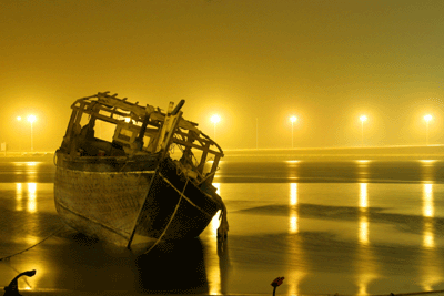 A traditional fishing boat lies at the sea-shore due to bad weather