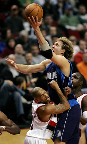 Dallas Mavericks forward Dirk Nowitzki (R) drives to the basket as Portland Trail Blazers guard Juan Dixon (L) defends during first quarter NBA action in Portland, Oregon March 9, 2006. [Reuters]