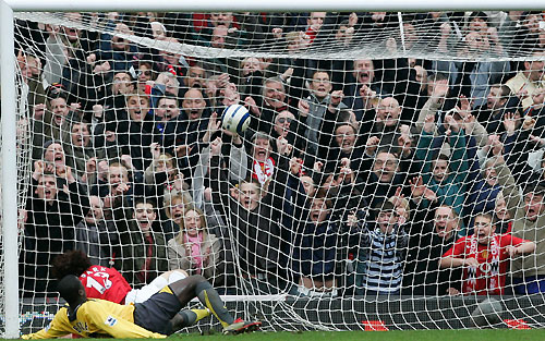 United's Ji-sung Park scores (top) past Arsenal's Emmanuel Eboue (bottom